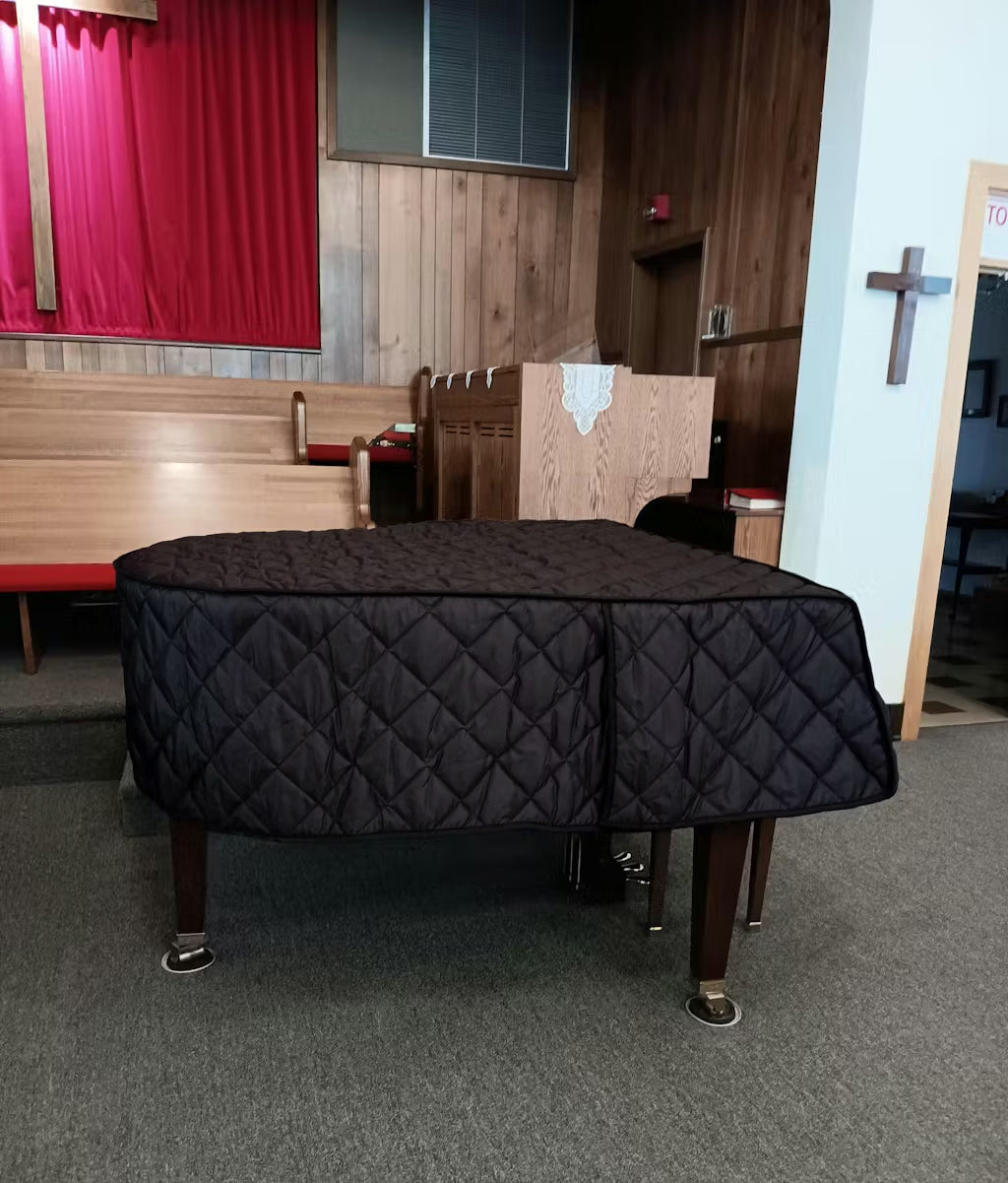 Black quilt piano cover on a Baldwin piano in a church