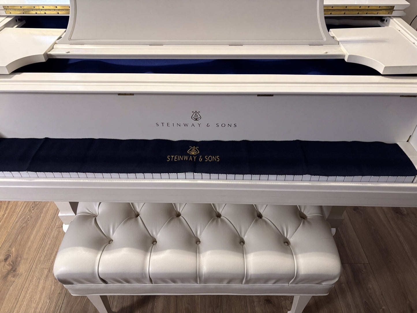 Steinway black felt piano key cover on white Steinway grand piano.